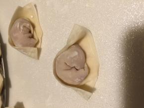 将馄饨皮对折，沾点水粘紧，窝过一点边儿，往回拐一下即可包好一个馄饨。