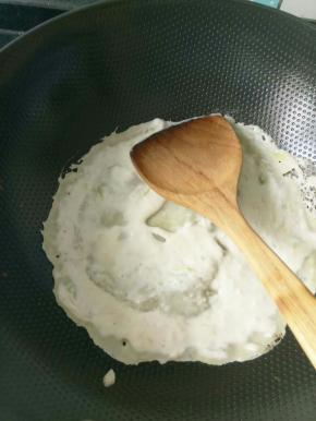 3.锅里倒少量的油，油热倒入一勺面糊，用铲子摊平