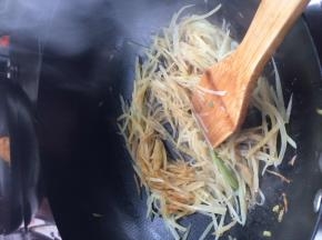把土豆放入锅中炒至八分熟，然后把凉皮放入锅中