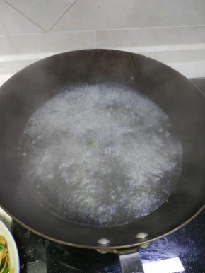 锅内烧热水，放入韭菜。先韭菜梗一端放入，再放入韭菜叶，焯水变软即可