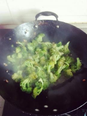 倒入焯好的西兰花，翻炒过程中均匀加入少许水以免粘锅。八分熟时加盐，快出锅时加入少许鸡精，以及剩下的1/3蒜粒，留一些最后拌可以让蒜味更香浓哦~