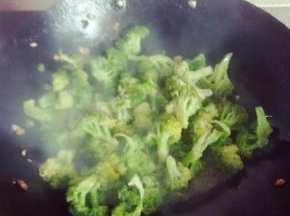 倒入焯好的西兰花，翻炒过程中均匀加入少许水以免粘锅。八分熟时加盐，快出锅时加入少许鸡精，以及剩下的1/3蒜粒，留一些最后拌可以让蒜味更香浓哦~