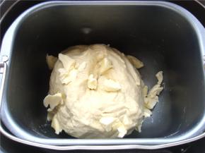 面包机桶里打入一个鸡蛋，倒入牛奶，盐，白糖（按先液体后粉类的顺序放入）倒入高粉，中间小坑里放入酵母粉。（避免酵母和盐直接接触影响活性）10分钟面成团后，按下暂停键，放入小块的黄油。