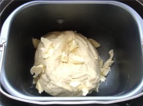 面包机桶里打入一个鸡蛋，倒入牛奶，盐，白糖（按先液体后粉类的顺序放入）倒入高粉，中间小坑里放入酵母粉。（避免酵母和盐直接接触影响活性）10分钟面成团后，按下暂停键，放入小块的黄油。