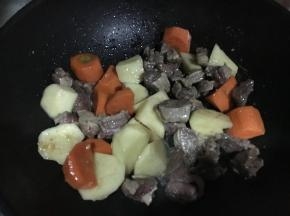 倒入胡萝卜和土豆进行翻炒，目的在于吸收丰富的油脂