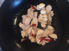 将杏鲍菇在油锅里煸软,煸到金色时,在锅里加入盐,糖,大蒜,干辣椒炒出香味。