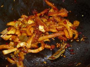 接着加入豆瓣炒香，再加入葱姜蒜和所有香料翻炒。随后加入一瓶盖料酒和两勺酱油翻炒均匀。