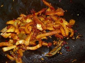 接着加入豆瓣炒香，再加入葱姜蒜和所有香料翻炒。随后加入一瓶盖料酒和两勺酱油翻炒均匀。