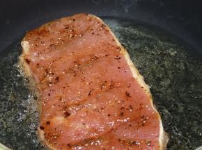 油锅小火热油，至插入筷子筷子周围有小泡包围时，放入猪扒煎，直到稍微闻到黑胡椒焦香味时，翻身继续煎。