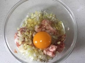 把葱姜切碎,打入一个鸡蛋和肉馅拌匀，打上劲