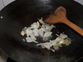 将油倒掉一些，留少许。小火热油，下姜葱蒜炒香，随后下入酸荞头，转中火翻炒至出酸香。