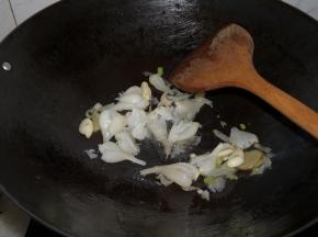 将油倒掉一些，留少许。小火热油，下姜葱蒜炒香，随后下入酸荞头，转中火翻炒至出酸香。