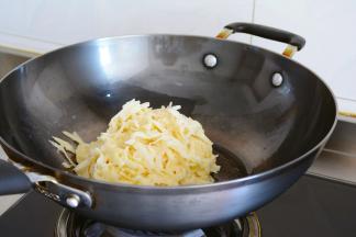 放油，均匀的涂开锅底~
放入调味好的土豆丝~
把火力调成中小火~