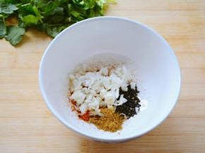 烧水汆烫豆皮等待的过程中准备拌菜的酱料~
容器中放入适量的辣椒粉，芝麻，十三香，以及蒜碎~
干料容易糊掉的放下面，蒜碎放到上面~