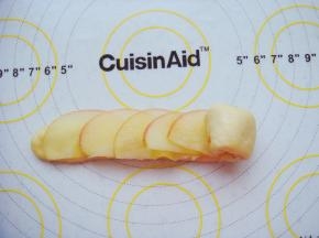 叠加摆放上苹果片从一端按紧卷起来。