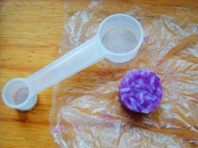 小量勺里铺上保鲜膜，填入米饭压实。拉出保鲜膜很轻松就刻出了小小的圆饭团，同样方法刻出原色饭团。