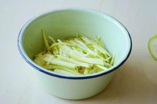 把过凉的金针菇攥净多余的水分与西葫芦丝放容器中。