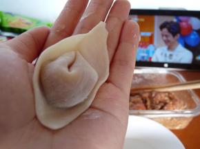 再将其中一角沾上一点水，将另一角叠上捏紧。一个云吞就做成了。