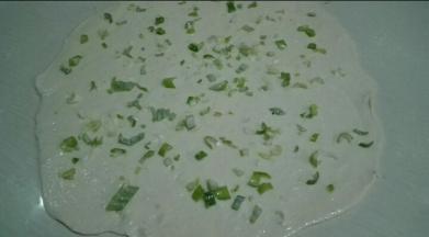 案板撒一层干粉，将面团擀成薄薄的圆形，刷一层花生油，撒上点盐，在撒上葱花碎