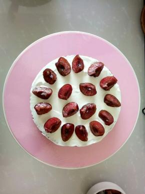 取一片蛋糕片，抹上奶油，摆上酒渍过的樱桃