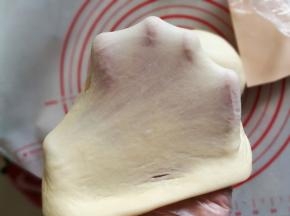 面团揉至光滑后，加入切块黄油，继续和面，揉至能拉出大片面膜，即扩展阶段。