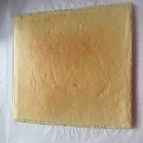 然后把晾凉的蛋糕拿过来，翻个面，两边各切一个斜面，等下卷起来好看又好卷。
然后在上面铺上淡奶油，我开始卷的那头铺的很多哦，别的地方薄薄一层就可以了。我加了芒果，你可以加自己喜欢的水果，也可以不加。