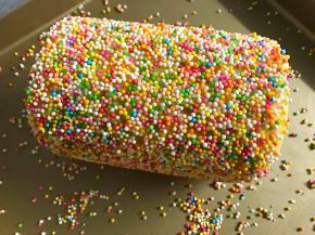 再用原色面团包起来，包好的心形表面再刷一层蛋白水，在彩色糖豆上滚一下，使得表面均匀地粘上糖豆，然后冷冻至硬。