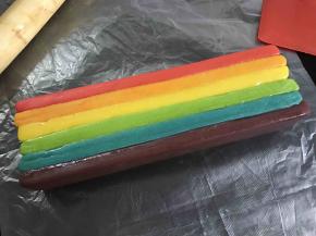 用刷子蘸蛋白刷在面片上把6色面片一层一层粘合起来。盖上保鲜膜用擀面杖轻轻地压实，放入冰箱冷冻。