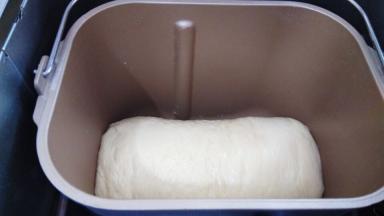 发酵完成以后把面团取出来，擀平排干净面团里的空气，再卷起来放回面包机继续发酵，这一步可以把面包搅拌刀取出来