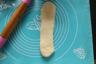 第二次擀卷：取一面团擀成长舌形，反面压薄底边，从上往下卷起。