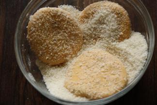 9取一个干净的容器，倒入面包糠，把南瓜饼放入面包糠，两面沾满面包糠。