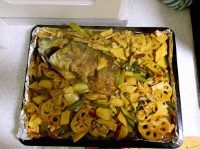 然后将炒好的配菜倒入烤好的鱼上面，淋上汤汁。再放入烤箱中层上小火200度15分钟左右。