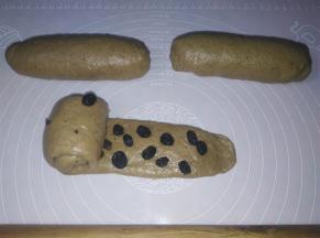 取一个面团擀成细长条，铺上提子干，从左到右再次卷起来