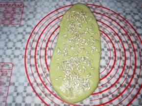取一个面团擀成大的饼皮，撒上适量的葵花籽，从下往上卷起来