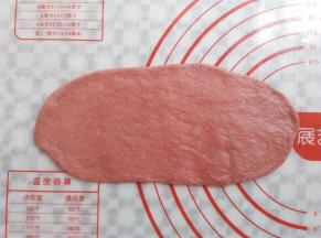 去一个红色面团擀成牛舌状的面皮