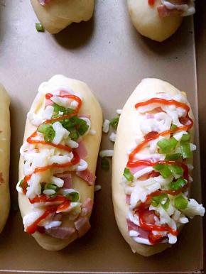 全部整形完毕后放入温暖湿润处进行二发（35度，湿度百分之80）。二发好后面包表面刷蛋液，撒上培根，挤沙拉酱，撒上芝士、香葱碎，挤番茄沙司。