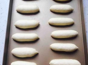 醒发好的面团擀成椭圆形，轻拍排气，两边按薄。翻过来从上向下卷起，搓成模具大小合适的面团。