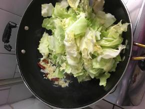 将蒜和辣椒拨到锅边，开大火，油温上来放入炒菜翻炒