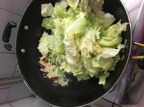 将蒜和辣椒拨到锅边，开大火，油温上来放入炒菜翻炒