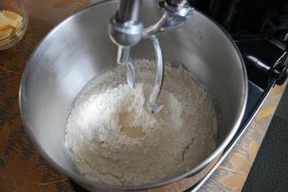 3把桶安装在厨师机上，启动1档和面，面团成团后，转入2档揉至扩展阶段加入软化的黄油，继续和面。