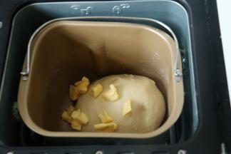 2启动一个和面程序，程序结束后面团揉至表面光滑，拉出较厚薄膜，加入软化的黄油。