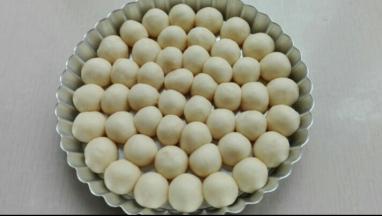 取出发酵好的面团，进行排气，均分为6克左右的小面团，搓圆，放置8寸派盘中摆好