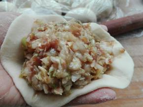 取一个剂子擀成皮，放入适量菜馅