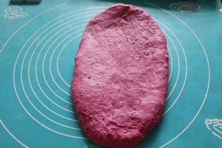 取出面团，排气滚圆，保鲜膜覆盖松弛15分钟！用排气杖，把面团擀成椭圆形。