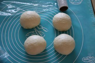 取出面团，挤压排气后，把面团平均分成四等分，滚圆，保鲜膜覆盖松弛15分钟。