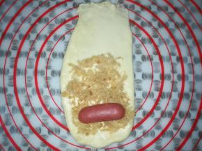 在面皮上抹上适量的沙拉酱，铺上肉松和半个迷你热狗肠