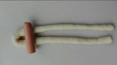 长度越长，兔子耳朵会更长，做出来的兔子也会更萌萌哒哈，如图，将火腿放在对折成U形的面团条上