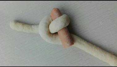 如图，将一条向上抬起压过香肠穿过去