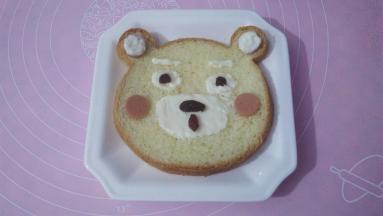 用沙拉酱画小熊的耳朵，眼睛，鼻子，葡萄干点缀鼻子，眼睛，火腿肠切圆片装饰小熊粉色的脸颊，呆萌的小熊就做好了