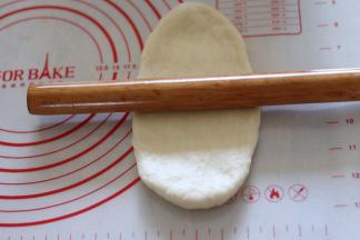 取一个面团擀成椭圆形，翻面从上往下卷起。